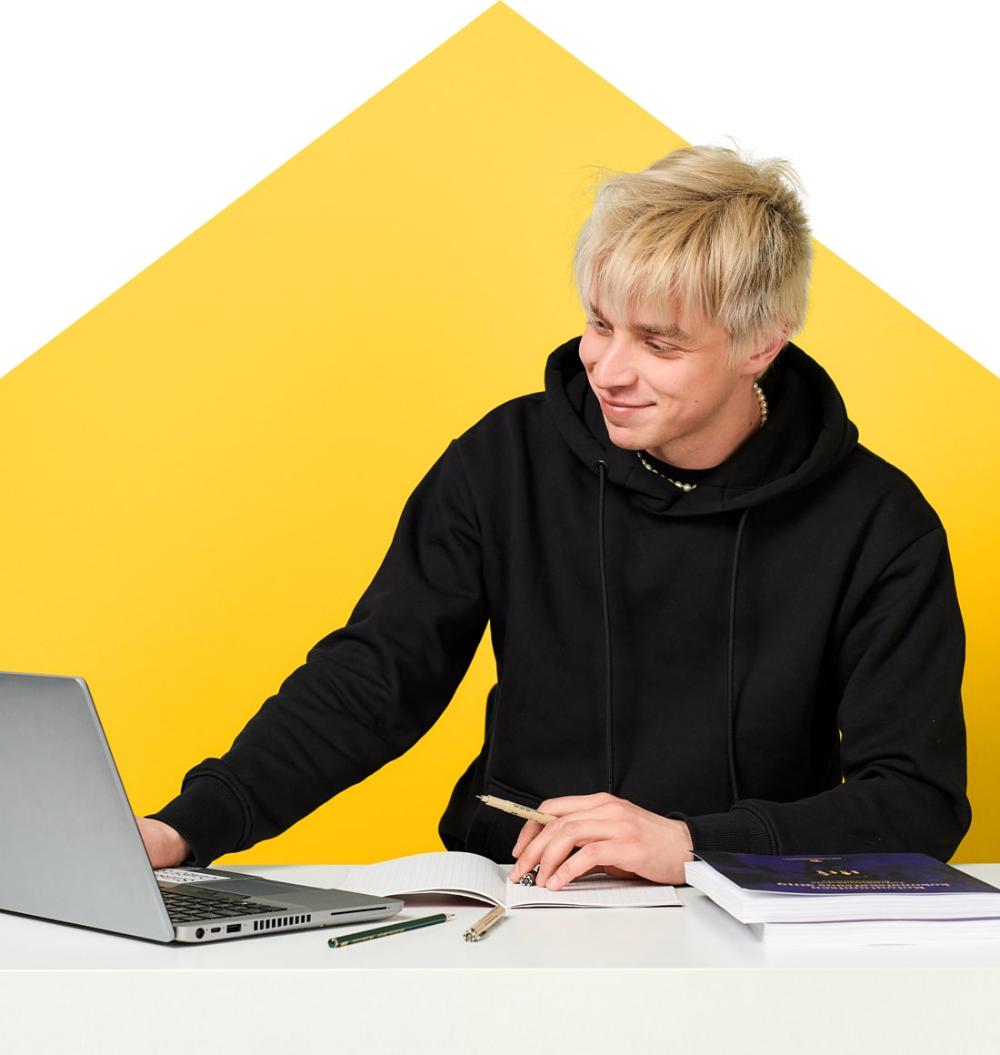 En man tittar på datorn med ett leende vid sitt skrivbord.